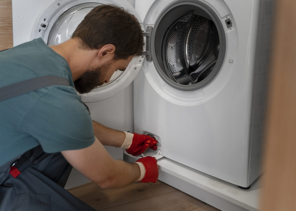 side view of man fixing washing machine leaking water